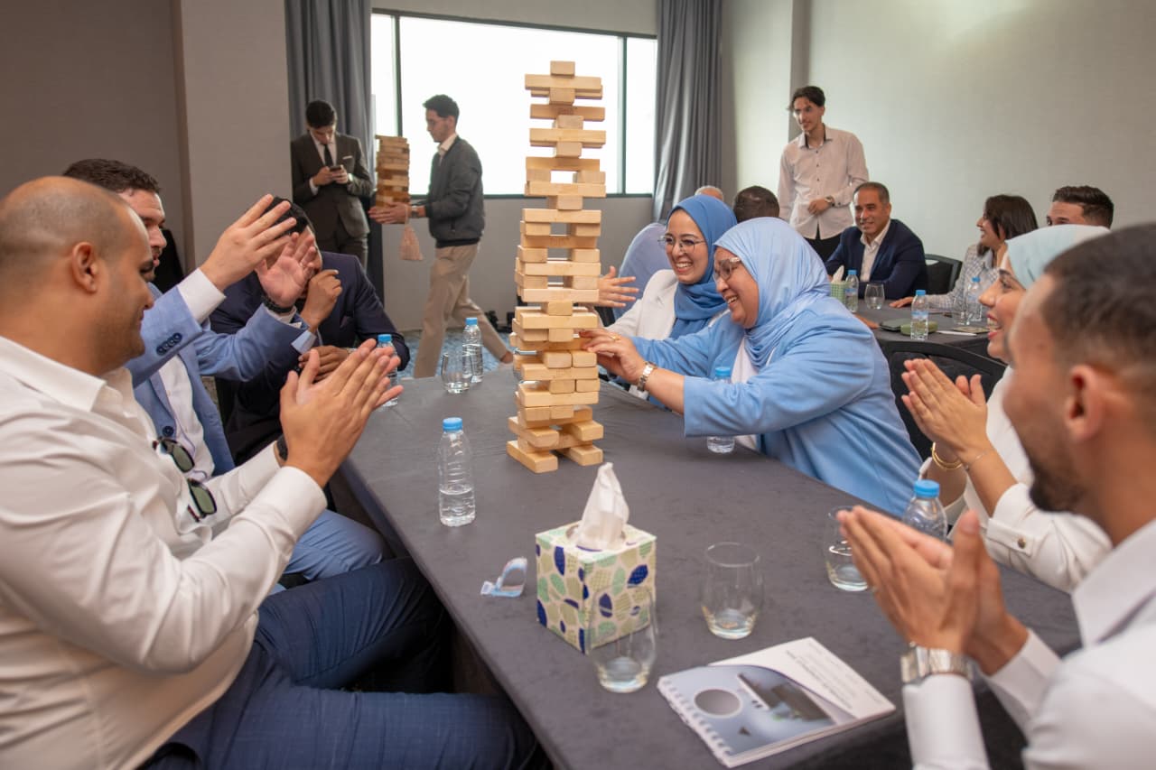 Équipe en plein team building autour d'une tour Jenga géante